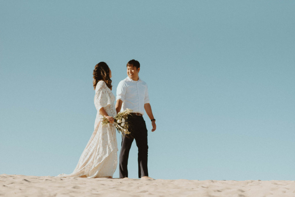bride and groom walking hand in hand during desert elopement