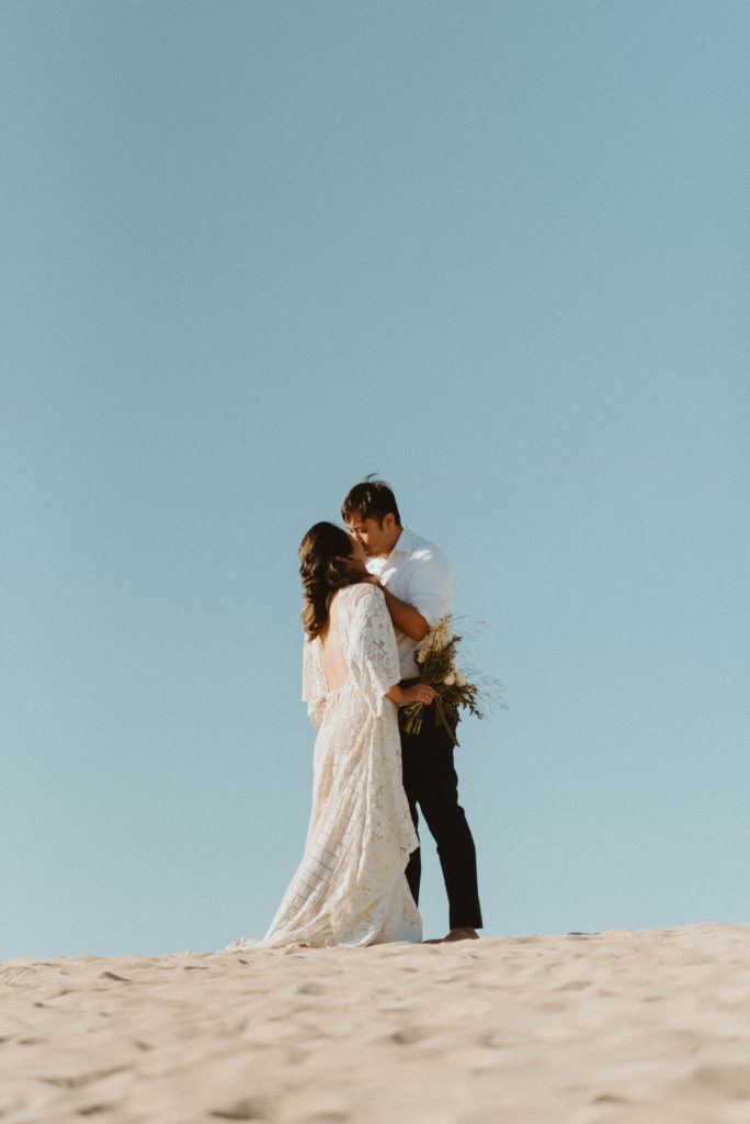 bride and groom kissing during desert elopement ceremony