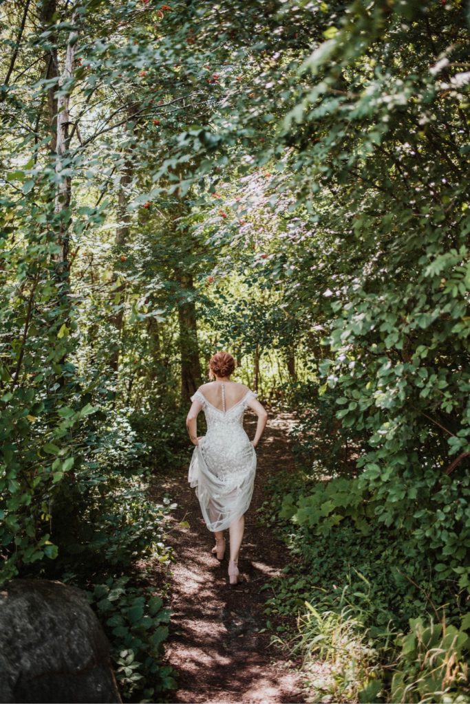 redheaded woman in wedding dress walking through forest trail