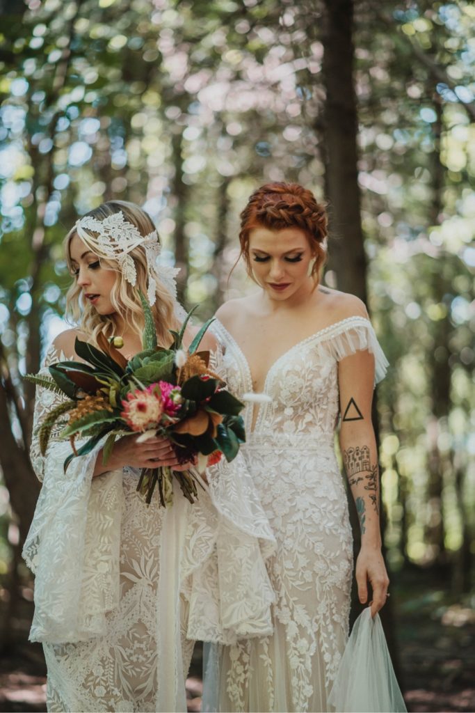 two brides holding bouquet in forest