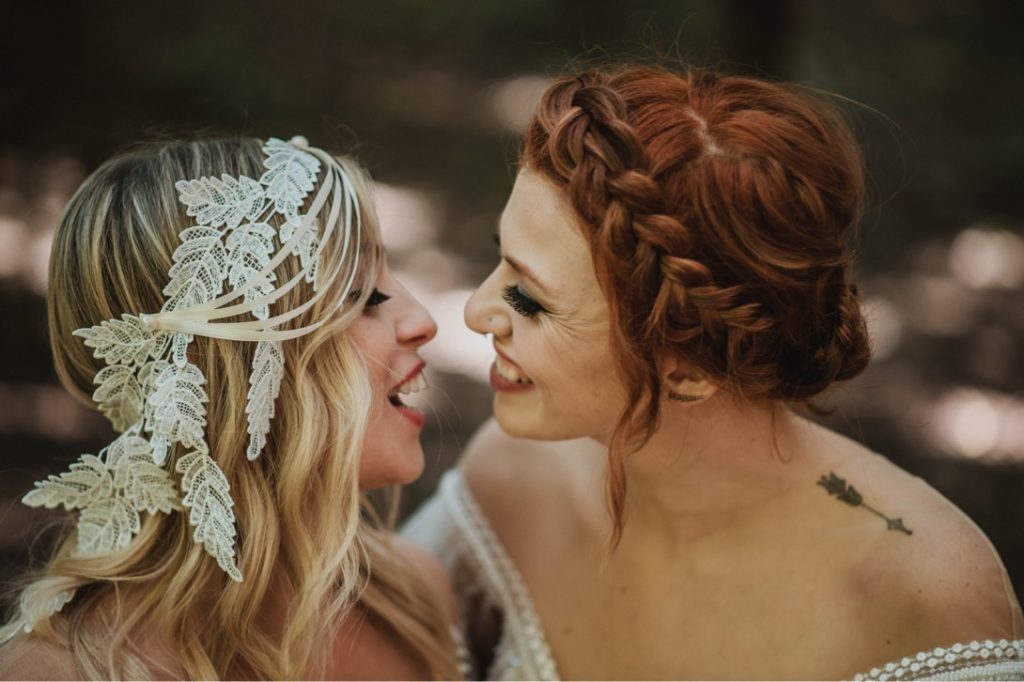 lesbian couple in wedding dresses laughing 