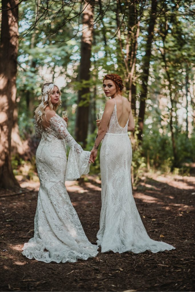 lesbian brides walking hand in hand through forest