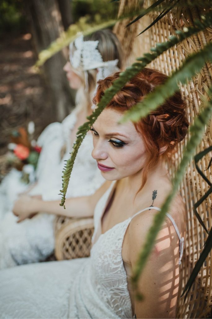 beautiful brides sitting holding hands in rattan chair