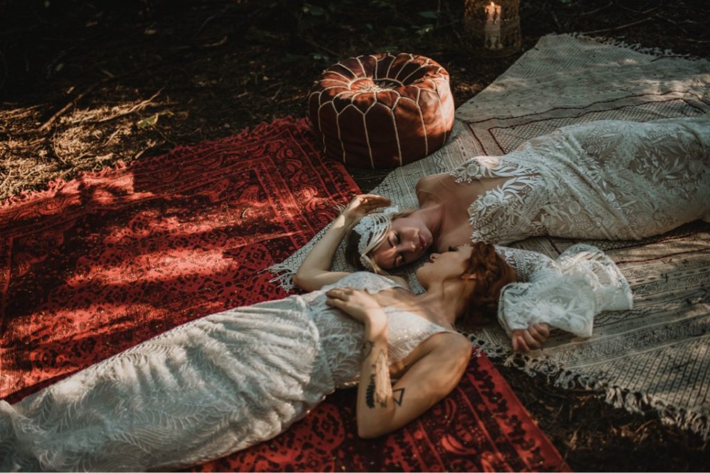 beautiful lesbian couple lying on persian rugs, sunlight streaming down across them