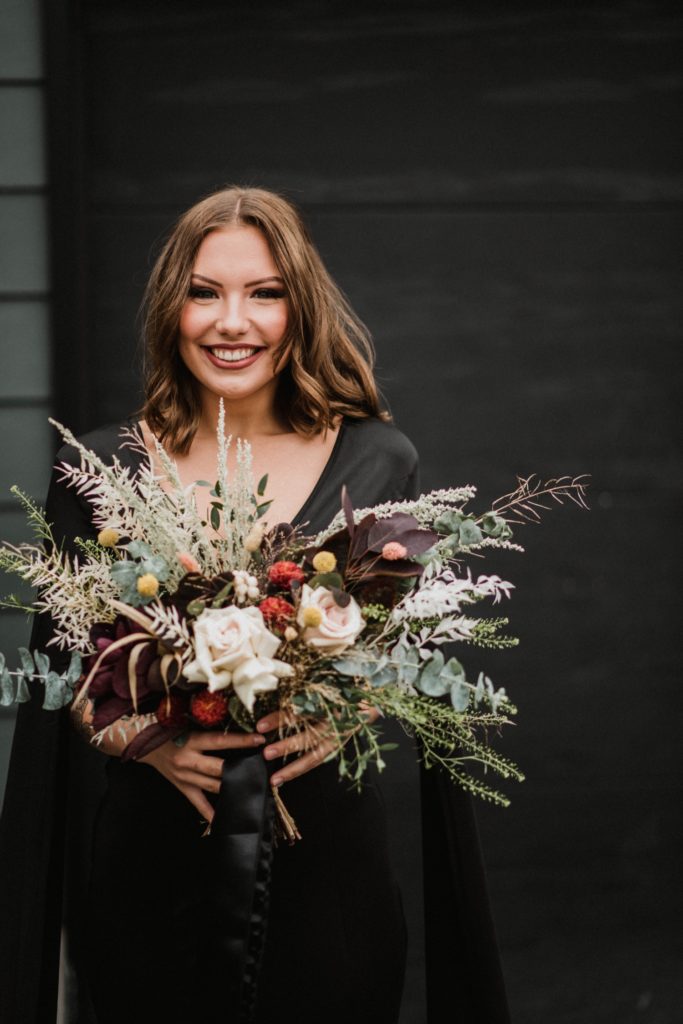 offbeat bride in black gown holding fall wedding bouquet