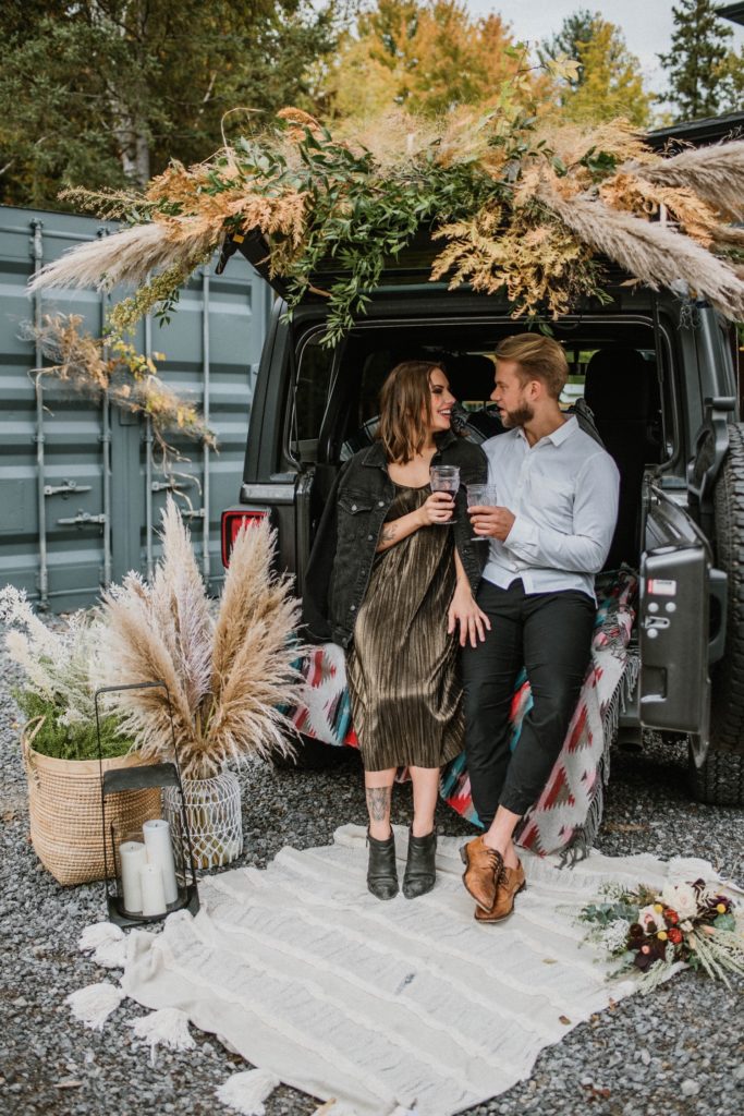 offbeat bride and groom having wine in boho Jeep