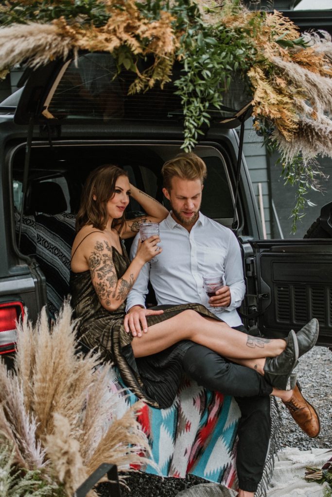 offbeat bride and groom having wine in boho Jeep