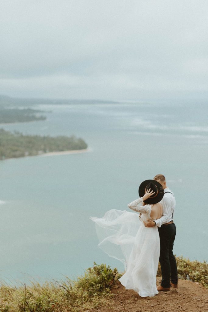 bride and groom overlooking the ocean on a windy wedding day