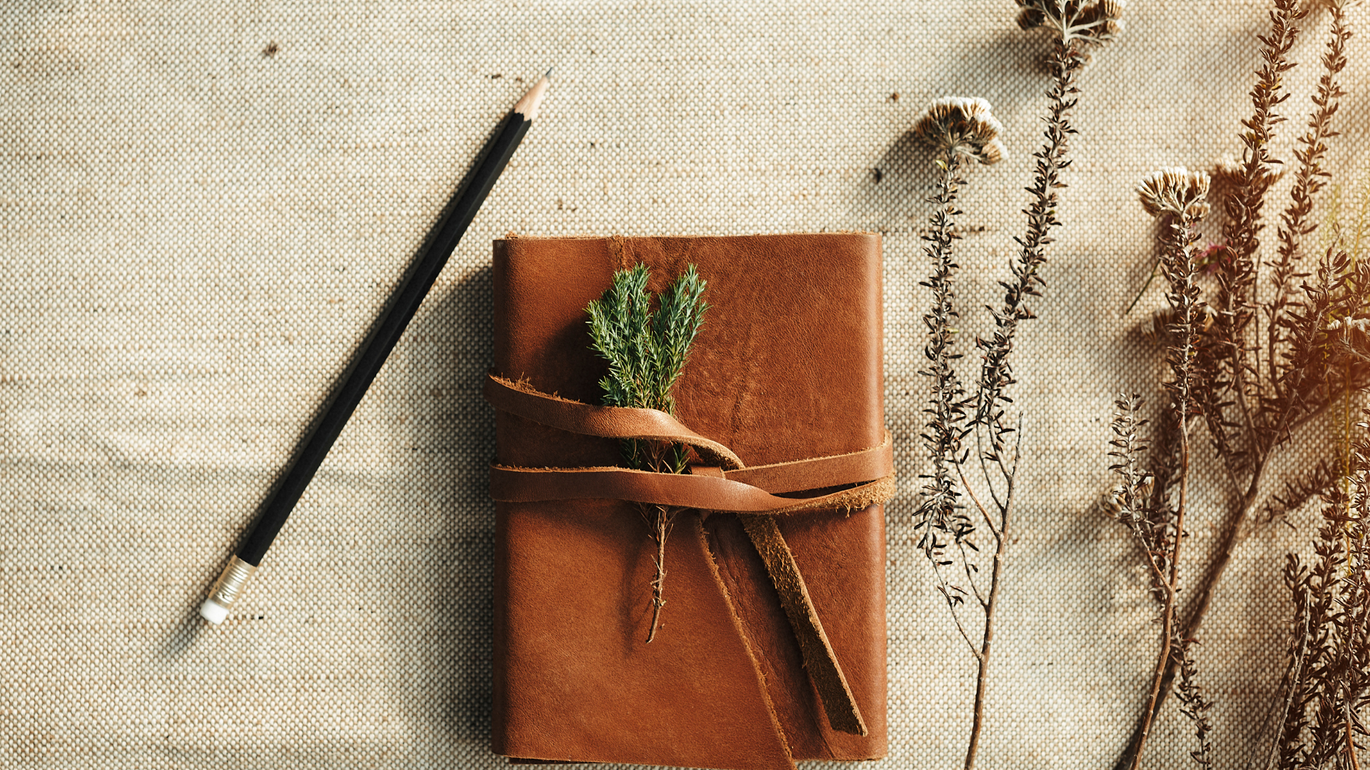 leather bound journal with pencil and plants