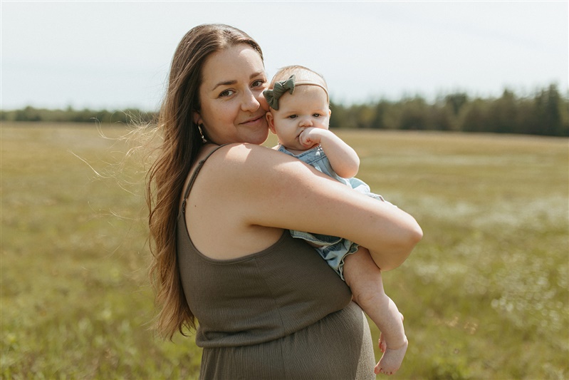 mom holding baby in sunny field
