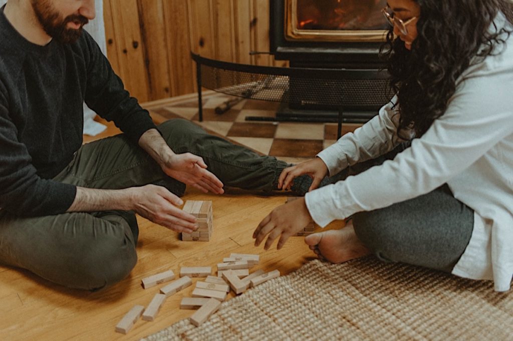 couple playing board games in front of fire