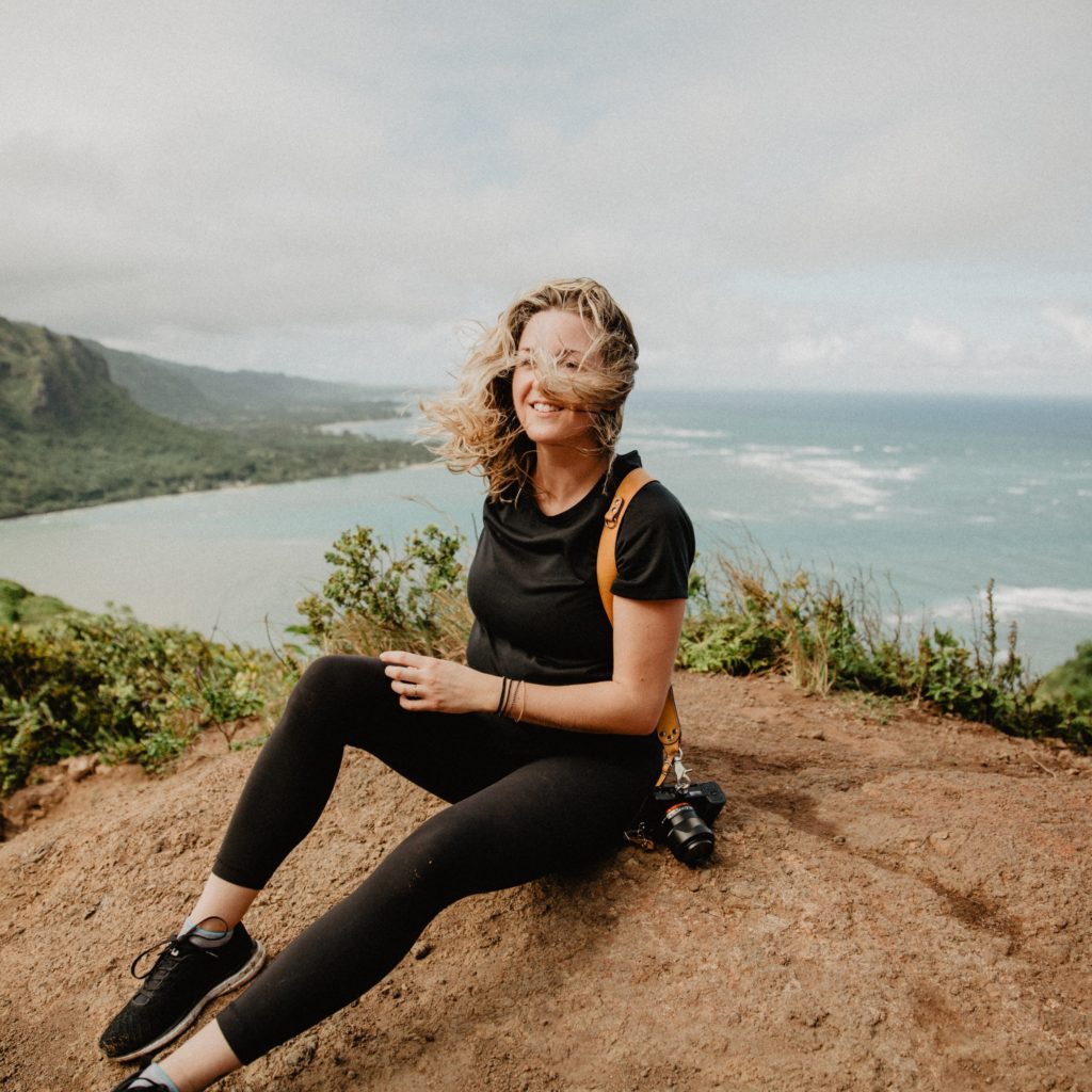 girl sitting on windy cliff with camera