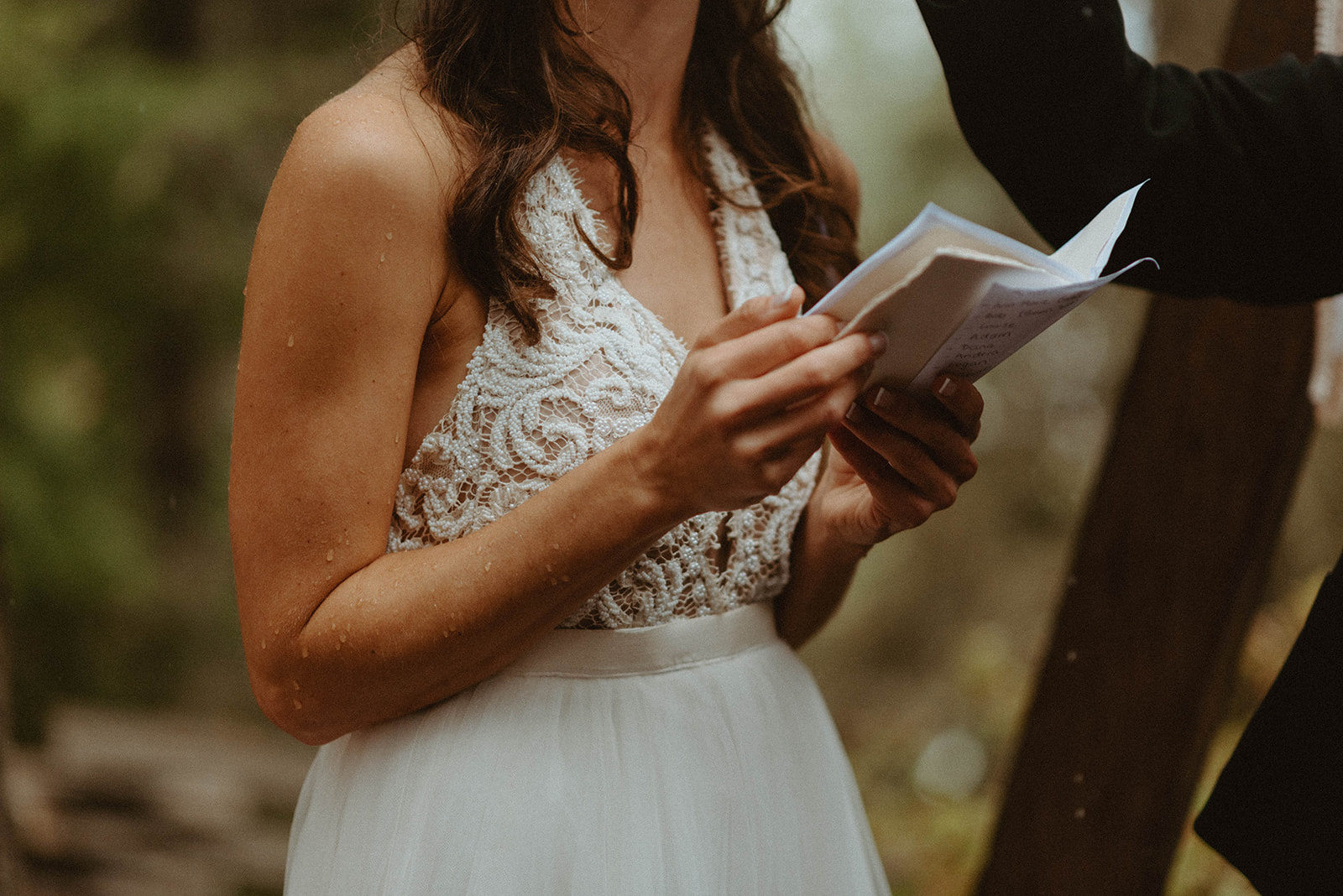 bride holding vow book in the rain