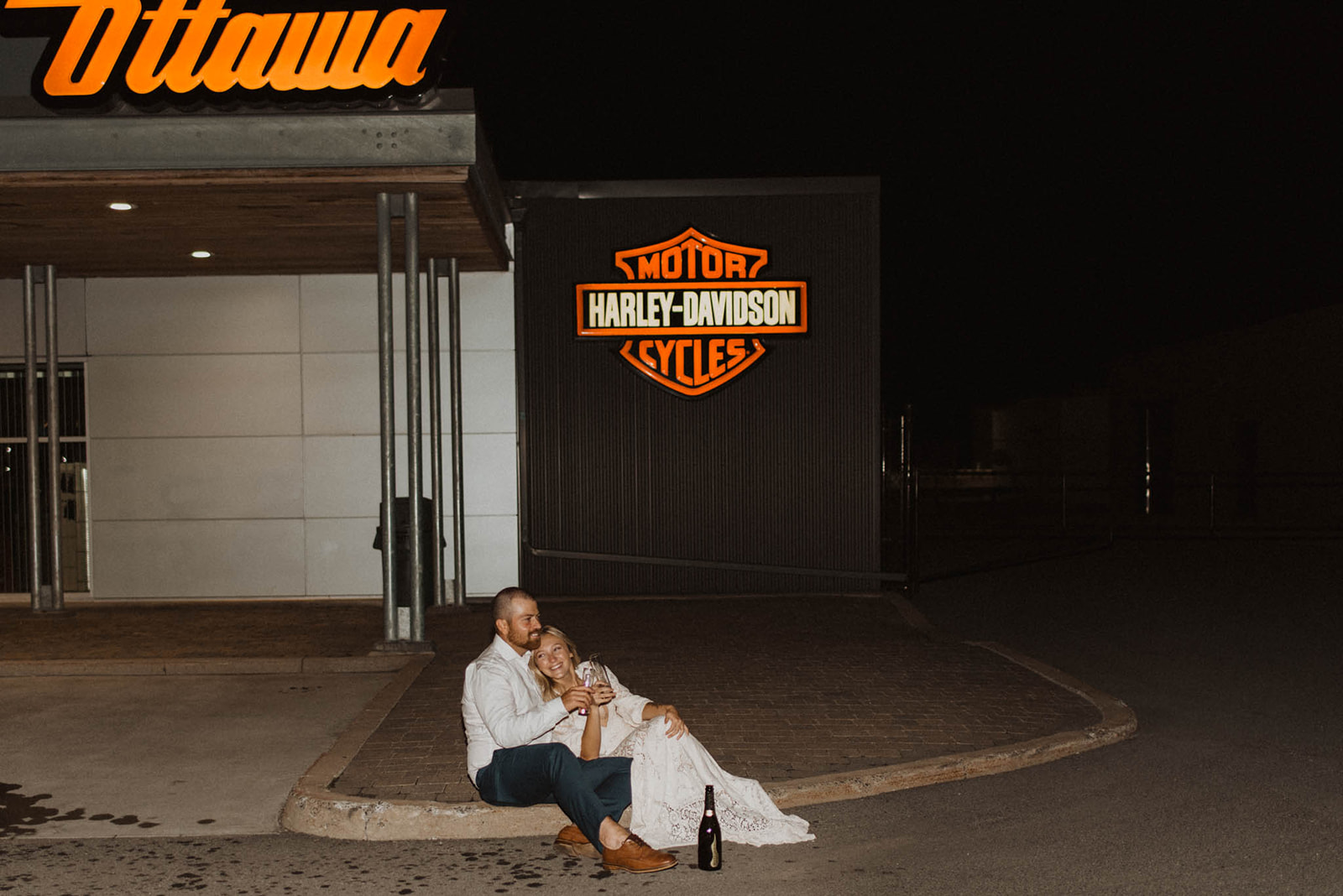bride and groom sitting outside Harley Davidson motorcycle shop