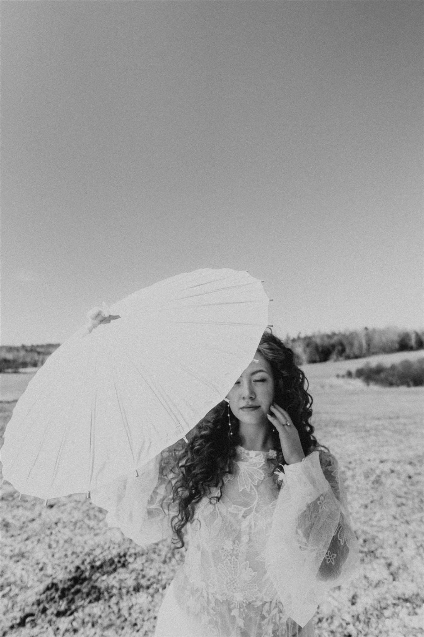 bride in lace gown holding paper parasol